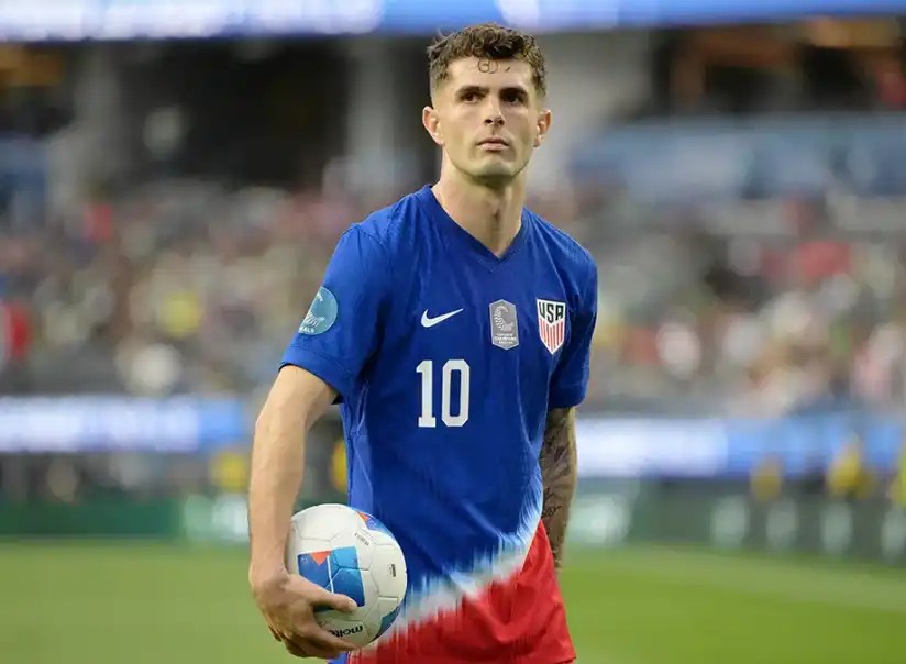 美國足球員普利西奇(Christian Pulisic)身穿美國國家隊球衣,手持足球站在球場上的畫面