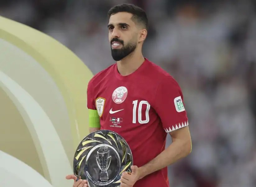 哈桑·海多斯（Hassan Al-Haydos）身穿卡達紅色球衣手持獎盤站在球場上